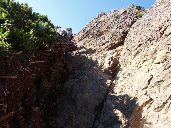 ハイマツ帯の脇に付けられた鎖に掴まりよじ登ります。ハイマツ帯と露岩の間を登り切った所が「赤岳の肩」です。