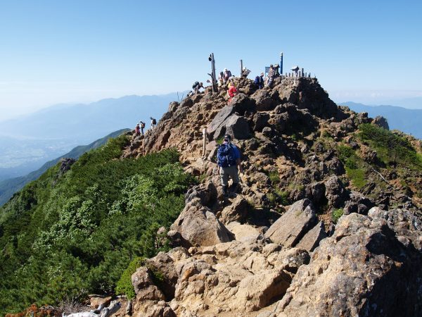 登山者でにぎわう赤岳頂上。展望抜群で、富士山から南アルプスが良く見えます。山頂には江戸時代から続く修験道の歴史を物語る赤岳神社の小祠が祀られています。