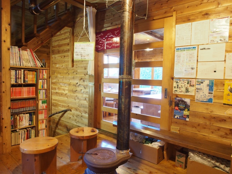受付を変えると小さな談話スペースがあり、達磨ストーブが迎えてくれます。書棚には漫画関係、登山関係の書籍などが置かれています。ドア越しに食堂があります。