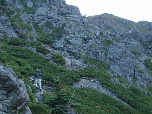左手上部にそそり立つ天狗岩は右手側からトラバースして登り上げます。登山者が取り付いている岩場の傾斜はさほどなく、足場はしっかりしているので難しくありません。