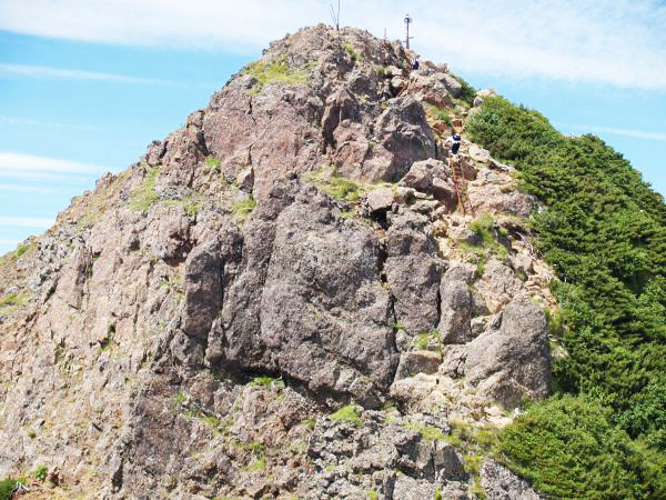 前の写真位置より望遠で山頂部を撮影。赤岳上部のはしごを登っている登山者が写っています。