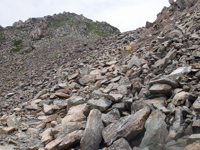 岩がゴロゴロした斜面を黄色のマークの上まで登ったら、向きを左に変えて登ります。