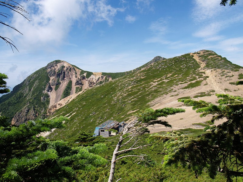 ここからの眺めは絶景で、根石山荘が箕冠山と根石岳のコルに建っています。右上は根石岳、その左奥に東天狗岳の山頂のみが見えています。左奥に見えるのは西天狗岳です。