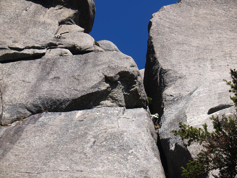 岩の割れ目の上部を登るクライマー